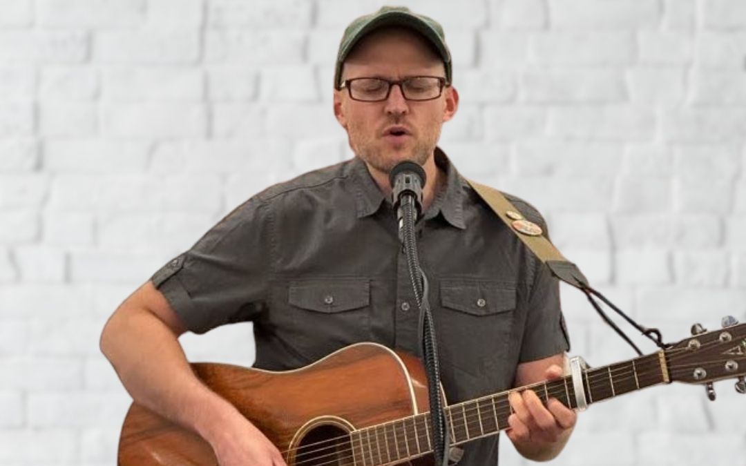 Songwriting - Photo of Kevin Basl performing with his guitar.